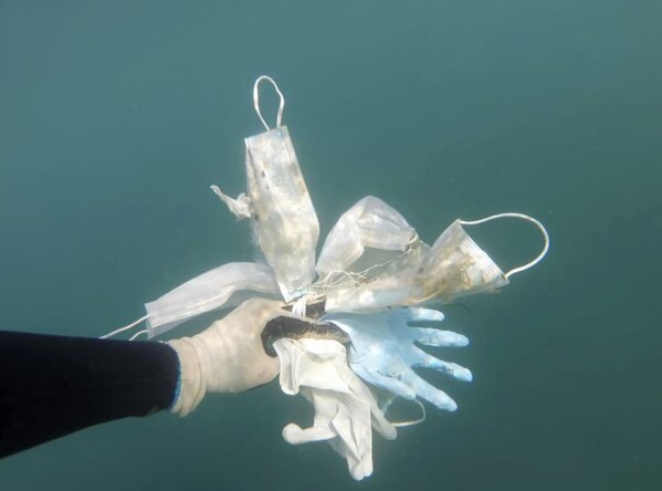 This photo taken on May 21, 2020 and provided Wednesday May 27, 2020 by environmental group Operation Mer Propre (Operation Clean Sea) shows a diver holding plastic gloves and face masks off Antibes, southern France. A French environmental group found this virus-era detritus littering the Mediterranean floor near the French Riviera resort of Antibes, and is trying to raise awareness and clean it up. (Operation Mer Propre via AP)