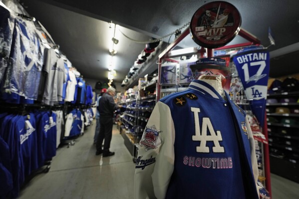 A Los Angeles Dodgers jacket is on display as a customer looks at baseball caps of the Dodgers at SELECTION, a sporting goods store in Shinjuku district of Tokyo, Thursday, Feb. 29, 2024. (AP Photo/Hiro Komae)
