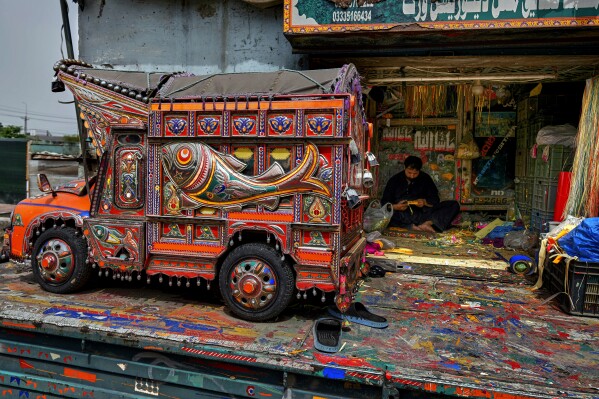 An artisan makes traditional patterns with colorful stickers used to decorate trucks at a yard for workshops in Rawalpindi, Pakistan, on Saturday, April 19, 2025. (AP Photo/Anjum Naveed)