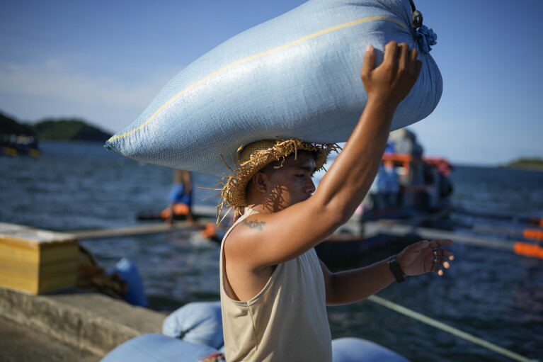 A worker carries a sack of rice at the coastal town of Santa Ana, Cagayan province, northern Philippines on Tuesday, May 7, 2024. The United States and the Philippines, which are longtime treaty allies, have identified the far-flung coastal town of Santa Ana in the northeastern tip of the Philippine mainland as one of nine mostly rural areas where rotating batches of American forces could encamp indefinitely and store their weapons and equipment within local military bases under the Enhanced Defense Cooperation Agreement, or EDCA. (AP Photo/Aaron Favila)