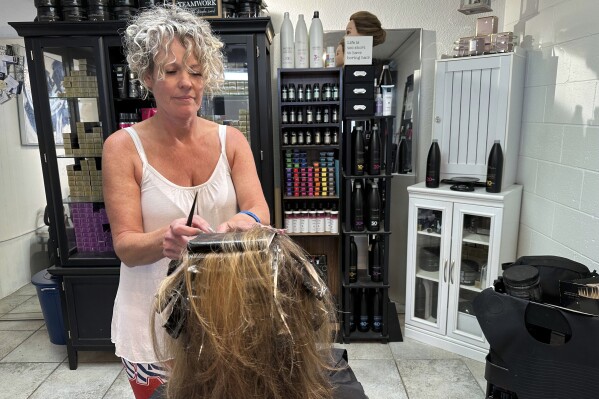 FILE - Christine Geiger cuts a customer's hair at her salon, July 12, 2023, in Traverse City, Mich. The hair salon is facing a discrimination charge from the state's Department of Civil Rights after Geiger posted on social media earlier this year that anyone identifying as other than a man or a woman is not welcome at her business. (AP Photos/John Flesher, file)