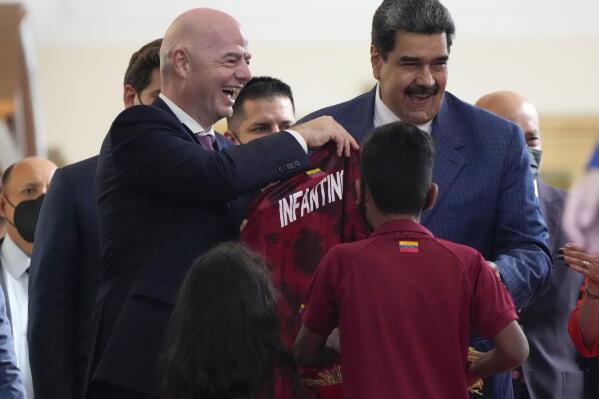 FIFA president Gianni Infantino, left, smiles after receiving the shirt of the Venezuelan soccer team with Venezuela President Nicolás Maduro, right, during his visit at Miraflores Presidential Palace in in Caracas, Venezuela , Friday , Oct 15, 2021. (AP Photo/Ariana Cubillos)