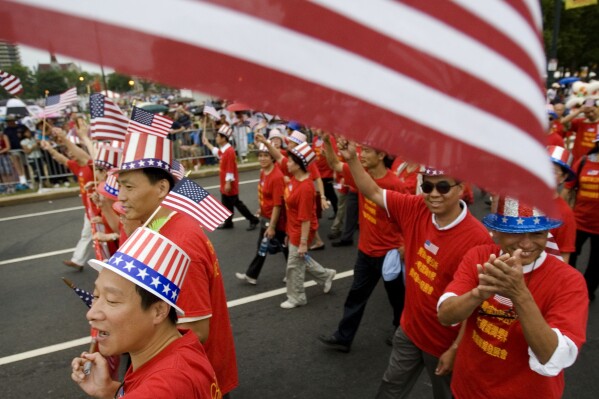 FILE - Tang De Wong, lower left, and other members of the Chinese Benevolent Association march in an Independence Day parade in Philadelphia, July 4, 2008. Flags proliferate every July Fourth, but it wasn't always a revered and debated symbol. Unlike the right to assemble or trial by jury, the flag's role was not prescribed by the founders: Flags would have been rare during early Independence Day celebrations and were so peripheral to early U.S. history that no original flag exists. (AP Photo/Matt Rourke, File)