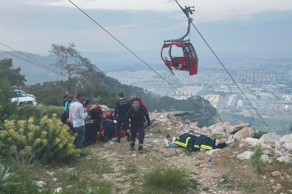 Rescue and emergency team members work with passengers of a cable car transportation system outside Antalya, southern Turkey, Friday, April 12, 2024. (Dia Images via AP)