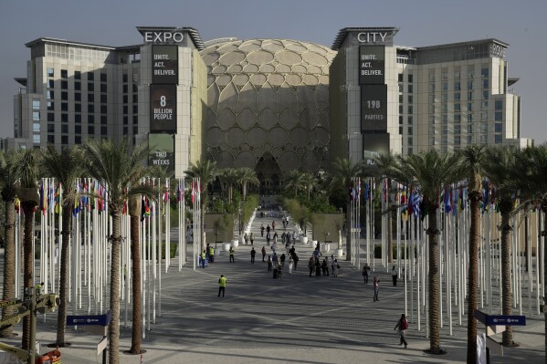 FILE - People walk through the venue for the COP28 U.N. Climate Summit with the Al Wasl Dome in the background at Expo City, Nov. 29, 2023, in Dubai, United Arab Emirates. (AP Photo/Joshua A. Bickel, File)