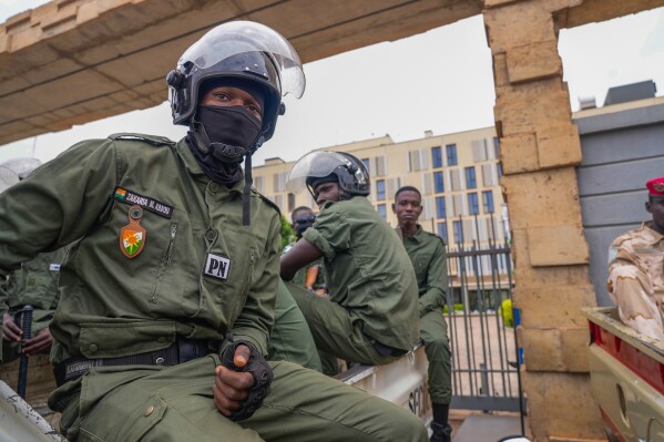 Nigerien police officers sit outside the customs offices in Niamey, Niger, Monday, Aug. 21, 2023. Around 300 trucks of food and other materials crossed into Niger from Burkina Faso with many arriving in the capital, Niamey Sunday, according to a regional custom's official. (AP Photo/Sam Mednick)