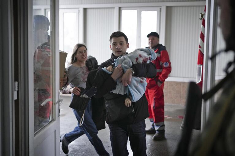 Marina Yatsko, left, runs behind her boyfriend Fedor carrying her 18 month-old son Kirill who was fatally wounded in shelling, as they arrive at a hospital in Mariupol, Ukraine, Friday, March 4, 2022. (AP Photo/Evgeniy Maloletka)