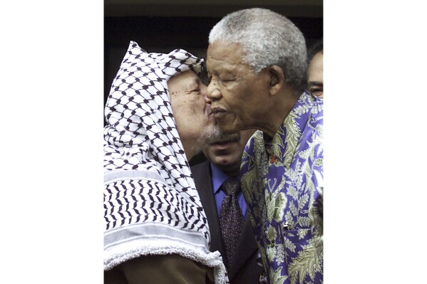 Late Palestinian leader Yasser Arafat, left, embraces the late former South Africa President Nelson Mandela, right, at a meeting in Johannesburg Thursday May 3, 2001.  (AP Photo/Denis Farrell, File)