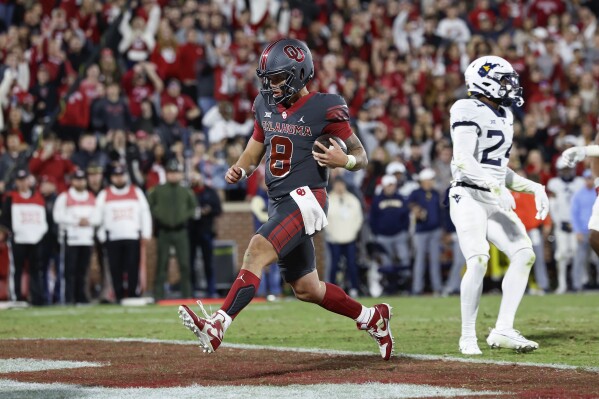 Oklahoma quarterback Dillon Gabriel (8) scores a touchdown against West Virginia during the second half of an NCAA college football game Saturday, Nov. 11, 2023, in Norman, Okla. (AP Photo/Alonzo Adams)