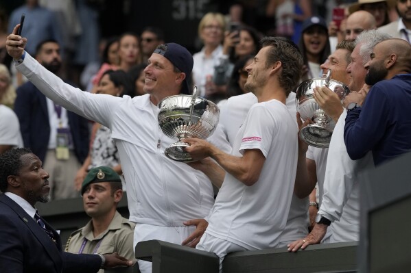 Britain's Neal Skupski and Wesley Koolhof of the Netherlands celebrate with family and friends after winning against Spain's Marcel Granollers and Argentina's Horacio Zeballos during the men's doubles final on day thirteen of the Wimbledon tennis championships in London, Saturday, July 15, 2023. (AP Photo/Alastair Grant)
