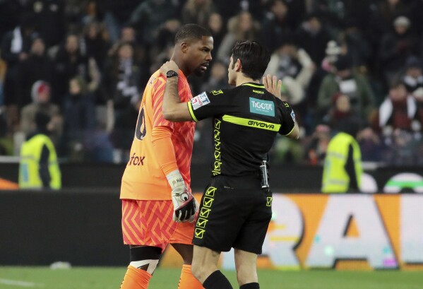 Referee Fabio Maresca, right, speaks to AC Milan's Mike Maignan during the Italian Serie A soccer match between Udinese and AC Milan that was suspended, at the Friuli stadium in Udine, Italy, Saturday, Jan. 20, 2024. Racist abuse aimed at AC Milan goalkeeper Mike Maignan prompted a top-tier Italian league game at Udinese to be suspended briefly during the first half. Maignan left the field after the insults which followed a goal for Milan. (Andrea Bressanutti/LaPresse via AP)