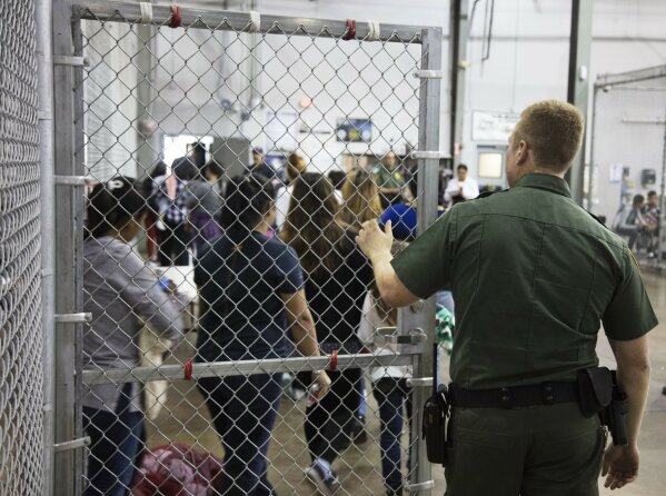 
              In this photo provided by U.S. Customs and Border Protection, a U.S. Border Patrol agent watches as people who've been taken into custody related to cases of illegal entry into the United States, stand in line at a facility in McAllen, Texas, Sunday, June 17, 2018. (U.S. Customs and Border Protection's Rio Grande Valley Sector via AP)
            