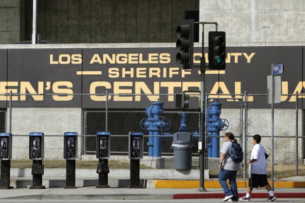 FILE - In this Sept. 28, 2011 photo, people walk past the Los Angeles County Sheriff's Men's Central Jail facility in Los Angeles. Up to one-third of the 12,000 inmates in Los Angeles County jails can’t get to their court appearances because of a shortage of functioning buses, and county supervisors this week advanced a proposal to try and fix the problem. (AP Photo/Damian Dovarganes, File)