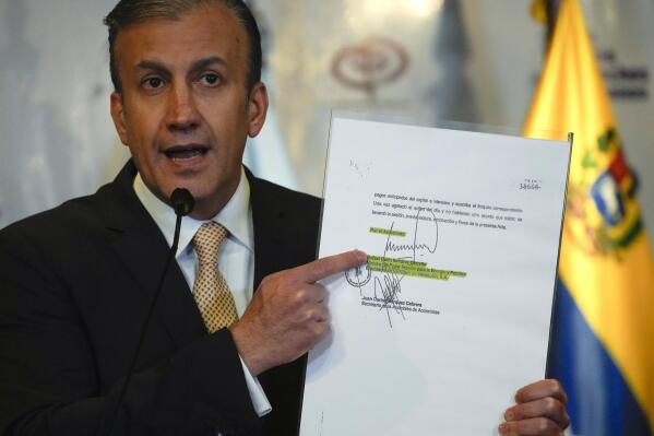 Venezuela's Petroleum Minister Tareck El Aissami holds up a document signed by former Oil Minister Rafael Ramirez, during a press conference at the Public Ministry, in Caracas, Venezuela, Tuesday, Aug. 30, 2022. El Aissami announced his government is seeking an international arrest warrant for former Oil Minister Rafael Ramirez who resides in Europe. (AP Photo/Ariana Cubillos)