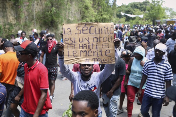 A protester holds up a sign that reads in French, "Security is a right, Haiti deserves it" during a protest against insecurity in Port-au-Prince, Haiti, Wednesday, April 2, 2025. (AP Photo/Odelyn Joseph)