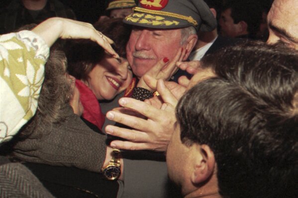 FILE - Former Chilean dictator and then-military commander Gen. Augusto Pinochet is embraced by a supporter as he meets with supporters who gathered at his home to greet him on the occasion of the 22nd anniversary of his taking the post as head of the Chilean armed forces, in Santiago, Chile, Aug. 23, 1995. As Chile marks the 50th anniversary Monday, Sept. 11, 2023 of the coup that brought Pinochet to power, polling shows more than one-third of Chileans today justify the military takeover of a democratically elected government that went on to violate human rights, murder opponents, cancel elections, restrict the media, suppress labor unions and disband political parties. (AP Photo/Santiago Llanquin, FILE)