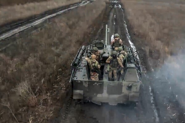 In this photo taken from video released by Russian Defense Ministry Press Service on Saturday, April 13, 2024, Russian Army soldiers ride their armoured vehicle to take positions and fire toward Ukrainian positions at an undisclosed location in Ukraine. (Russian Defense Ministry Press Service via AP)