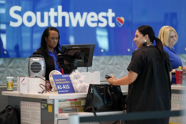 A Southwest airlines customer service representative, left, assists a traveler at the ticketing counter at Love Field airport, Friday, May 19, 2023, in Dallas. The unofficial start of the summer travel season is here, with airlines hoping to avoid the chaos of last year and travelers scrounging for ways to save a few bucks on pricey airfares and hotel rooms.(AP Photo/Tony Gutierrez)