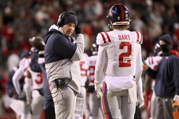 Mississippi coach Lane Kiffin talks with quarterback Jaxson Dart (2) during a timeout in the first half of an NCAA college football game against Arkansas on Saturday, Nov. 19, 2022, in Fayetteville, Ark. (AP Photo/Michael Woods)