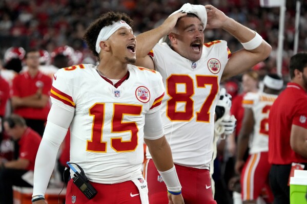 Kansas City Chiefs quarterback Patrick Mahomes (15) and tight end Travis Kelce (87) cheer from the sidelines during the first half of an NFL preseason football game against the Arizona Cardinals, Saturday, Aug. 19, 2023, in Glendale, Ariz. (AP Photo/Rick Scuteri)