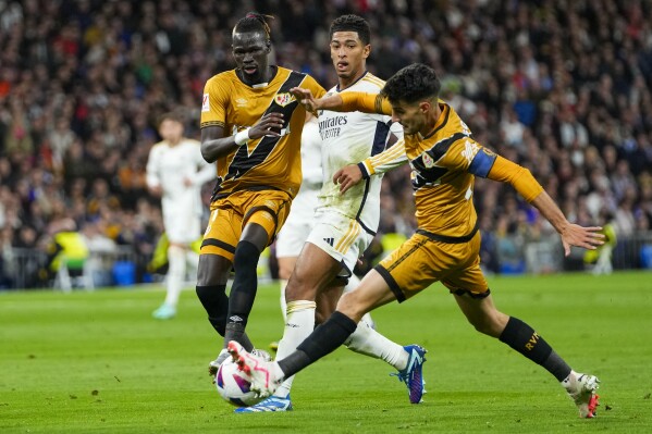 Real Madrid's Jude Bellingham, center, duels for the ball with Rayo's Oscar Valentin, left, and Rayo's Pathe Ciss during a Spanish La Liga soccer match between Real Madrid and Rayo Vallecano at the Santiago Bernabeu stadium in Madrid, Spain, Sunday, Nov. 5, 2023. (AP Photo/Manu Fernandez)