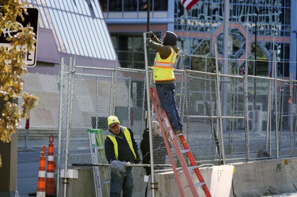 Workers install barbed wire on fencing outside the Hennepin County Government Center, Wednesday, Feb. 23, 2021 in Minneapolis, as part of security preparation for the trial of former Minneapolis police officer Derek Chauvin. The trial is slated begin with jury selection on March 8. Chauvin is charged with murder the death of George Floyd during an arrest last May in Minneapolis. (AP Photo/Jim Mone)