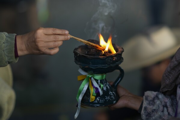 A Purepecha Indigenous woman lights a copal incense during a rest stop in the mountains by a group walking from Erongaricuaro, where residents kept a flame alive for one year, to Ocumicho in Michoacan state, Mexico, Wednesday, Jan. 31, 2024. To mark the new year, based on an ancient lunar calendar, a new flame will be lit during a “New Fire” ceremony on Feb. 2. (AP Photo/Eduardo Verdugo)