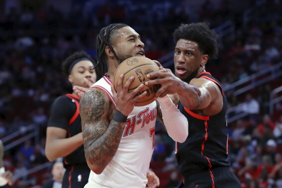 Houston Rockets forward Cam Whitmore, center, drives to the basket as Toronto Raptors forward Thaddeus Young, right, reaches in to block during the first half of an NBA basketball game Friday, Feb. 2, 2024, in Houston. (AP Photo/Michael Wyke)