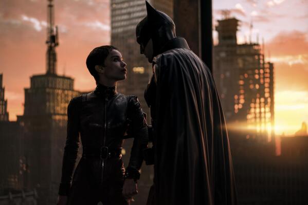 This image released by Warner Bros. Pictures shows Zoe Kravitz, left, and Robert Pattinson in a scene from "The Batman."  “The Batman” is still going strong three weeks into its theatrical run, with a tight grip on the top spot at the box office. Robert Pattinson’s debut as the Dark Knight earned an additional $36.8 million over the weekend, according to studio estimates Sunday, March 20, 2022. It also slid past the $300 million mark ahead of projections. (Jonathan Olley/Warner Bros. Pictures via AP)