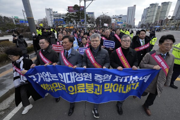 Doctors march toward the presidential office during a rally against the government's medical policy in Seoul, South Korea, Sunday, Feb. 25, 2024. The South Korean government on Wednesday warned thousands of striking doctors to return to work immediately or face legal action after their collective walkouts caused cancellations of surgeries and disrupted other hospital operations. (AP Photo/Ahn Young-joon)
