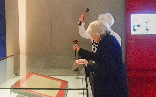 In this photo provided by Just Stop Oil on Friday, May 10, 2024, two activist Judy Bruce, a retired biology teacher and Reverend Sue Parfitt, foreground as they target the protective enclosure around the historic Magna Carta document with a hammer at the British Library, in London. Two environmental activists have attacked a glass case containing an original copy of the Magna Carta at the British Library. Minor damage was caused to the reinforced box but the historic document was unscathed. (Just Stop Oil via AP)