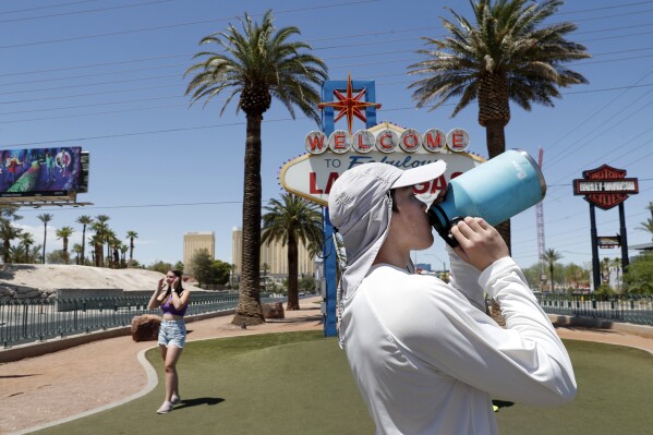 Dean Leano bebe agua mientras hace una pausa luego de fotografiar turistas en el famoso letrero de bienvenida en Las Vegas, el jueves 6 de junio de 2024. (Steve Marcus/Las Vegas Sun vía AP)