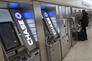 Chase Bank ATMs are shown, Thursday, March 25, 2021, in New York. JPMorgan Chase said, Wednesday, April 13, 2022, its first quarter profits dropped by 42% from last year, partly because the bank had to write down nearly $1.5 billion in assets due to higher inflation and the Russian-Ukrainian War. The nation’s largest bank by assets said it earned a profit of $8.3 billion, or $2.63 per share, down from a profit of $14.3 billion, or $4.50 a share, in the same period a year earlier.(AP Photo/Mark Lennihan)