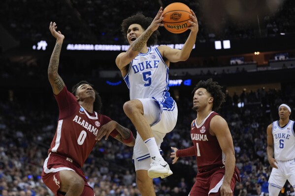 Duke guard Tyrese Proctor (5) goes up for a shot against Alabama guard Labaron Philon (0) and guard Mark Sears (1) during the first half of an Elite Eight round NCAA college basketball tournament game, Saturday, March 29, 2025, in Newark, N.J. (AP Photo/Julia Demaree Nikhinson)