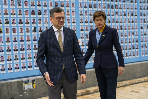 Ukraine Foreign Minister Dmytro Kuleba, left, leads his Latvia counterpart Baiba Braze after placing flowers at a memorial wall of Ukrainian soldiers killed during the war at Saint Michael cathedral in Kyiv, Ukraine, Friday, April 26, 2024. Braze visited Kyiv on her first foreign trip to discuss aid for Ukraine, including a plan to build drones. (AP Photo/Francisco Seco)