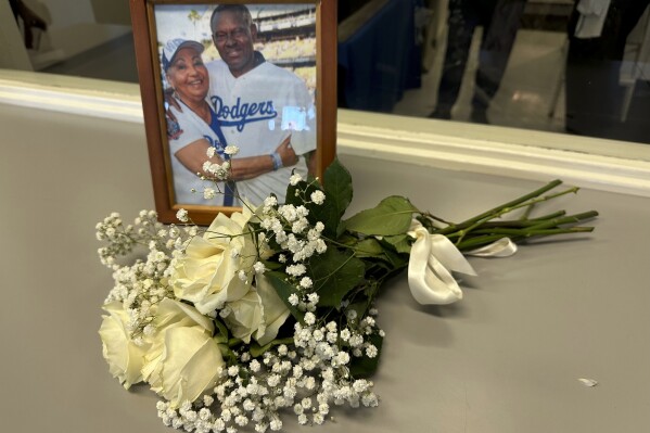 A framed photo of Margarita and Manny Mota along with a bouquet of white roses sits in the Dodger Stadium press box on Saturday, Sept. 23, 2023, in Los Angeles. Margarita Mota, the wife of retired Los Angeles Dodgers outfielder Manny Mota and matriarch of a baseball family, died Saturday, according to her son José Mota. (AP Photo/Beth Harris)
