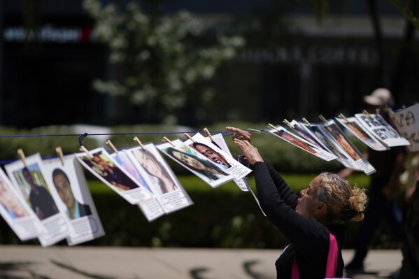 FILE - A woman hangs a portrait of a missing person on a makeshift line along Reforma Avenue during a march demanding the government do more to locate their loved ones, marking International Day of the Disappeared, in Mexico City, Wednesday, Aug. 30, 2023. Almost 112,000 people are missing in Mexico. President Andrés Manuel López Obrador claims that is an overcount, but a new U.N. report published Tuesday, Oct. 3, 2023, suggests the number may be even greater. (AP Photo/Eduardo Verdugo, File)