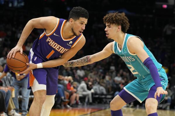 Phoenix Suns guard Devin Booker (1) is pressured by Charlotte Hornets guard LaMelo Ball during the second half of an NBA basketball game, Sunday, Dec. 19, 2021, in Phoenix. (AP Photo/Rick Scuteri)
