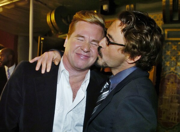Val Kilmer, left, gets a kiss from fellow "Kiss Kiss Bang Bang" cast member Robert Downey Jr. at the West Coast premiere of the film in Los Angeles on Oct. 18, 2005.