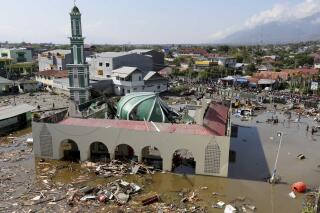 In this Sunday, Sept. 30, 2018, file photo, people survey the mosque damaged in a massive earthquake and a tsunami in Palu, Central Sulawesi, Indonesia. On Tuesday, February 7, 2023, The Associated Press reported on posts misrepresenting video of the tsunami as showing Turkey after its Feb. 6 earthquake. (AP Photo/Tatan Syuflana, File)