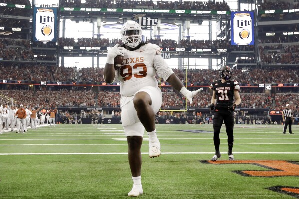 Texas Longhorns defensive lineman T'Vondre Sweat (93) strikes a pose in the end zone after catching a touchdown pass from quarterback Quinn Ewers during the first quarter of the Big 12 Championship NCAA college football game against Oklahoma State at AT&T Stadium in Arlington, Texas, Saturday, Dec. 2, 2023. (Tom Fox/The Dallas Morning News via AP)