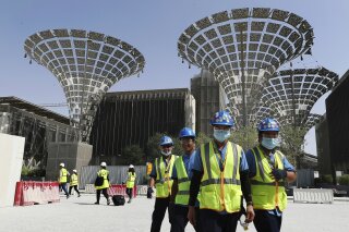 FILE - In this Oct. 8, 2019, file photo, technicians walk at the under construction site of the Expo 2020 in Dubai, United Arab Emirates. Dubai's Expo 2020 world's fair will be postponed to Oct. 1, 2021, over the new coronavirus pandemic, a Paris-based body behind the events said Monday, May 4, 2020. (AP Photo/Kamran Jebreili, File)