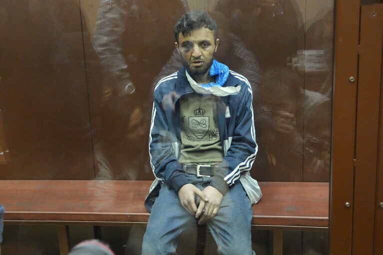 FILE - Dalerdzhon Mirzoyev, a suspect in the Crocus City Hall shooting, sits in a defendants’ cage in Basmanny District Court in Moscow, Russia, on March 24, 2024. The attack on the concert hall, the bloodiest assault on Russian soil in two decades, appears to be setting the stage for an increasingly harsh response by President Vladimir Putin. Four suspects in the attack appeared in court showing signs of brutal treatment while in custody. (AP Photo/Alexander Zemlianichenko, File)
