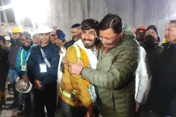 This handout photo provided by the Uttarakhand State Department of Information and Public Relations shows Pushkar Singh Dhami, right, Chief Minister of the state of Uttarakhand, greeting a worker rescued from the site of an under-construction road tunnel that collapsed in Silkyara in the northern Indian state of Uttarakhand, India, Tuesday, Nov. 28, 2023. Dhami said eight workers were rescued so far on Tuesday. The laborers are being pulled out through a passageway made of welded pipes which rescuers previously pushed through dirt and rocks. (Uttarakhand State Department of Information and Public Relations via AP)