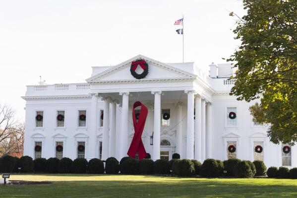 The North Portico of the White House is adorned with a huge red ribbon to commemorate the annual World AIDS Day, Wednesday, Dec. 1, 2021, in Washington. The Biden administration in its new HIV/AIDS strategy is calling racism "a public health threat" that must be fully recognized as the world looks to end the epidemic. (AP Photo/Manuel Balce Ceneta)
