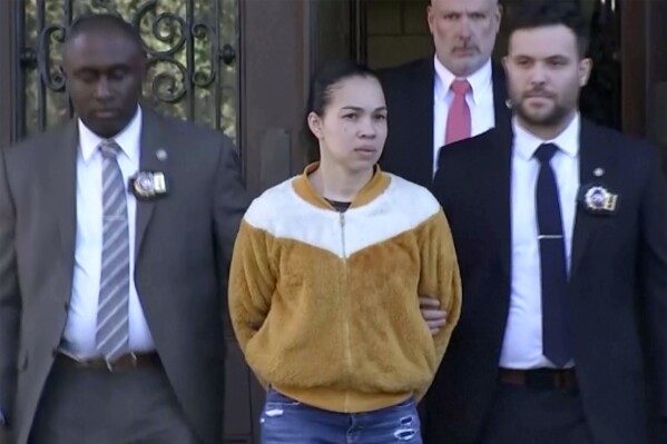 In this photo from video, Grei Mendez, center, is escorted by law enforcement personnel from a New York Police station, Tuesday, Sept. 19, 2023, in New York. Mendez, a day care operator and a man who rented a room from her are facing federal charges after the death of a 1-year-old exposed to fentanyl inside the day care. (WABC-TV via AP)