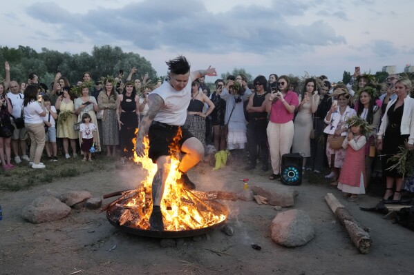 A Ukrainian man jumps over fire during a traditional Ukrainian celebration of Kupalo Night, in Warsaw, Poland, on Saturday, June 22, 2024. Ukrainians in Warsaw jumped over a bonfire and floated braids to honor the vital powers of water and fire on the Vistula River bank Saturday night, as they celebrated their solstice tradition of Ivan Kupalo Night away from war-torn home. (AP Photo/Czarek Sokolowski)