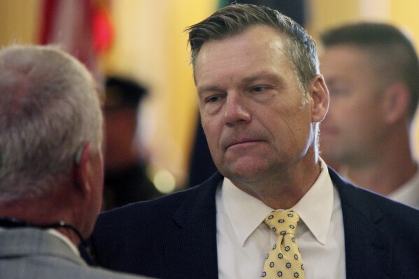 FILE - Kansas Attorney General Kris Kobach participates in a ceremony honoring fallen law enforcement officers, Friday, May 3, 2024, at the Statehouse in Topeka, Kan. Kansas is one of 15 states that filed a federal lawsuit Thursday, Aug. 8, 2024, against the Biden administration over a rule that is expected to allow 100,000 immigrants brought to the U.S. illegally as children to enroll next year in the federal Affordable Care Act's health insurance. (AP Photo/John Hanna, File)