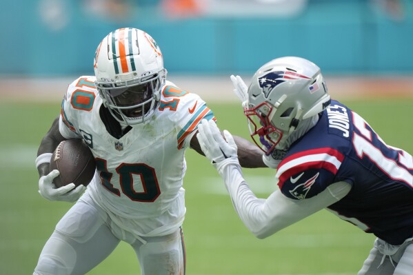 Miami Dolphins wide receiver Tyreek Hill (10) holds off New England Patriots cornerback Jack Jones (13) during the first half of an NFL football game, Sunday, Oct. 29, 2023, in Miami Gardens, Fla. (AP Photo/Wilfredo Lee)
