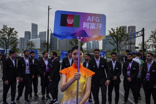 FILE - A volunteer holds up country's sign for Afghan men's only team during a welcoming ceremony at the 19th Asian Games in Hangzhou, China, Wednesday, Sept. 20, 2023. In the first Asian Games since the Taliban regained control of Afghanistan, two teams of athletes are arriving in the Chinese city of Hangzhou, looking very different. One, sent from Afghanistan where women are now banned by the Taliban from participating in sports, consists of about 130 all-male athletes, a Taliban-appointed spokesman for the Afghanistan’s Olympic Committee told The Associated Press. Another, competing under the black, red and green flag of the elected government the Taliban toppled in 2021, is drawn from the diaspora of Afghan athletes around the world, and includes 17 women. (AP Photo/Louise Delmotte, File)